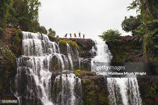 some people pose atop a waterfall. - bolaven plateau stockfoto's en -beelden