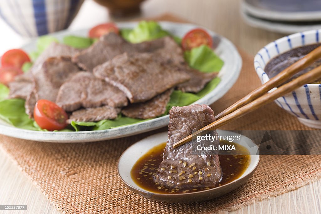 Dipping Broiled Beef into Korean Barbeque Sauce
