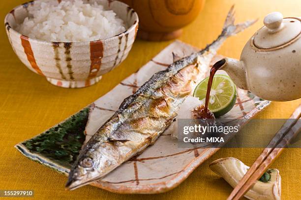pouring soy sauce on grilled pacific saury and grated daikon - saury stock pictures, royalty-free photos & images