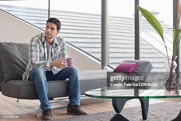 man sitting on a couch and drinking coffee - adult man brussels stock pictures, royalty-free photos & images