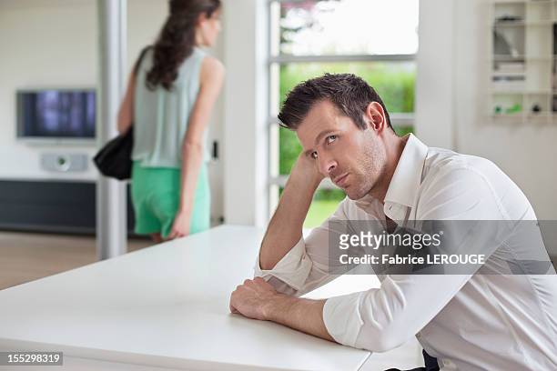 man sitting at a table with a woman leaving the home - ignoring fotografías e imágenes de stock