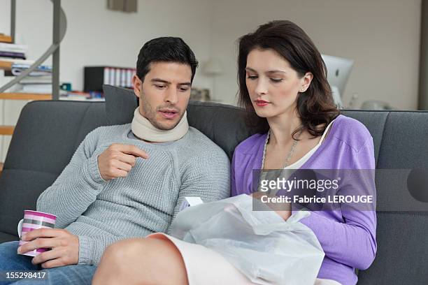 woman giving medicine to her husband suffering from neckache - cervical collar stock pictures, royalty-free photos & images