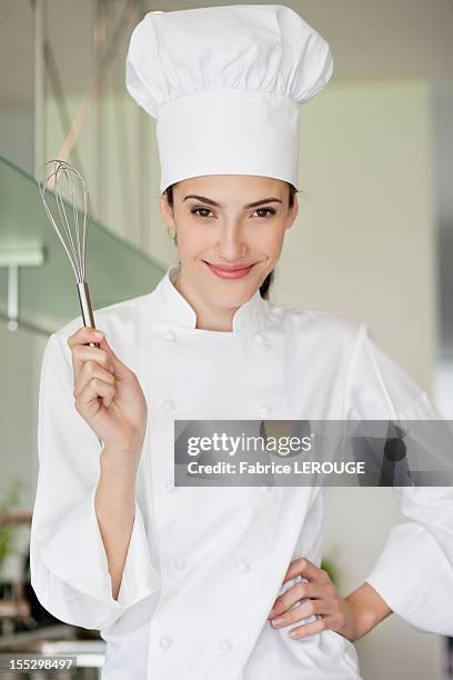 happy female chef holding a wire whisk - kochmütze stock-fotos und bilder