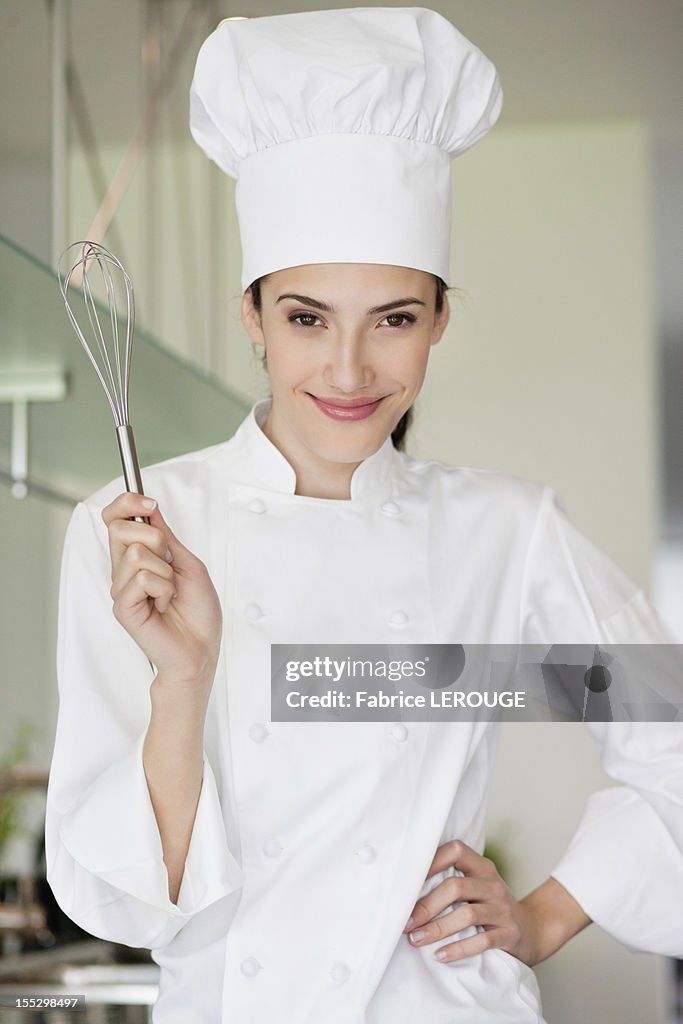 Happy female chef holding a wire whisk