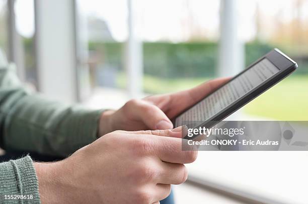 close-up of a man's hand holding a digital tablet - lector de libros electrónicos fotografías e imágenes de stock