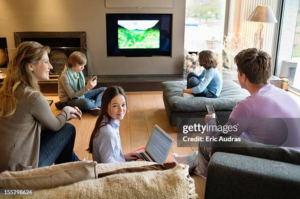 family using electronic gadgets in a living room - famiglia multimediale foto e immagini stock