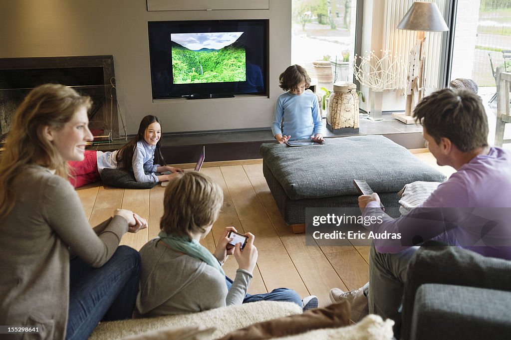 Family using electronic gadgets in a living room