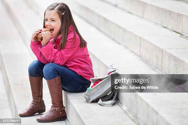 schoolgirl sitting on the steps and eating pain au chocolat - pain au chocolat stock-fotos und bilder