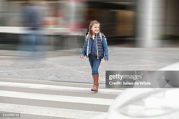 schoolgirl crossing a road - weggucken stock-fotos und bilder