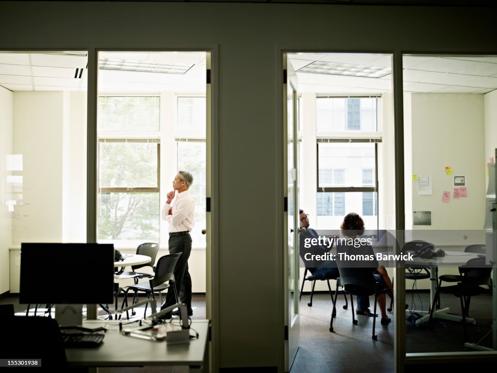 Coworkers working in adjoining conference rooms