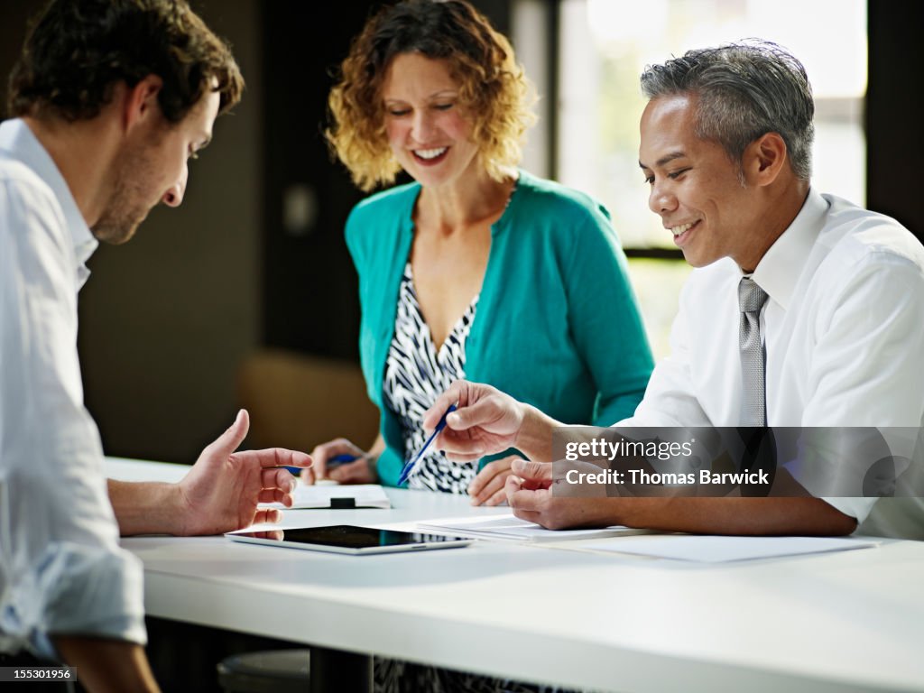 Coworkers discussing project in office smiling
