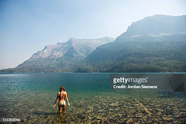 a female about to take a swim in a cool lake. - parque nacional glacier fotografías e imágenes de stock