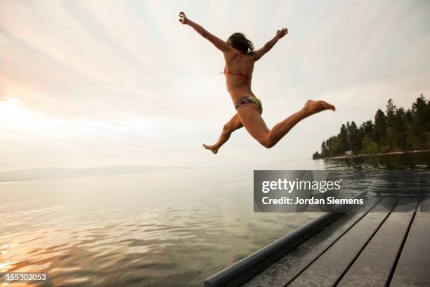 a female leaps into the cool water of a lake. - woman jumping lake bildbanksfoton och bilder