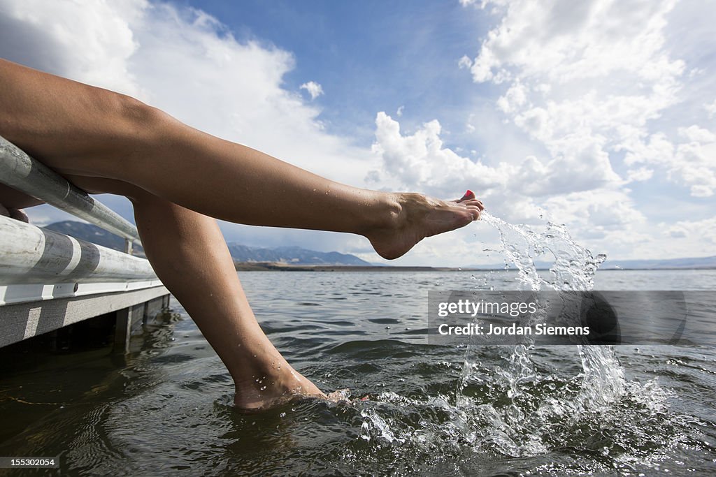 A woman splashing her feet in a lake.