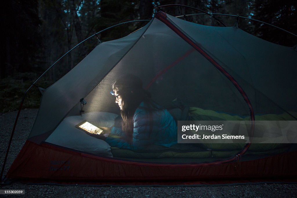 A female using an tablet computer in her tent.