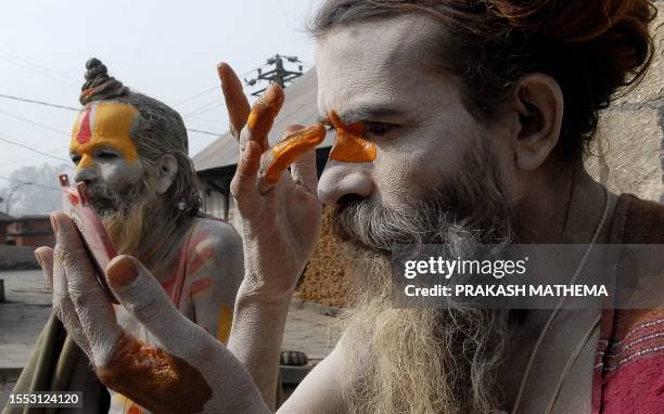 Nepalese Hindu sadhu - holy man - smears coloured paste onto his body at the Pashupatinath in Kathmandu on January 26, 2009. Dozens of sadhus live...