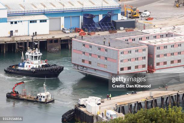 The Bibby Stockholm migrant barge is manoeuvred after arriving at Portland Harbour on July 18, 2023 in Portland, England. The Bibby Stockholm arrives...