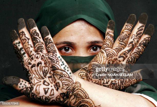 An Indian Muslim woman poses showing her hands decorated with Mehendi during 'Chand Raat' or 'Night of the Moon' in Hyderabad, 24 October 2006,...