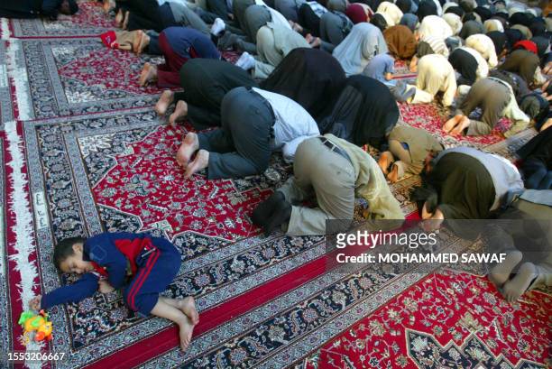 Child sleeps as Shiite Muslims take part in the Friday noon prayers at the Imam Hussein shrine in the southern holy city of Karbala, 120 kms south of...