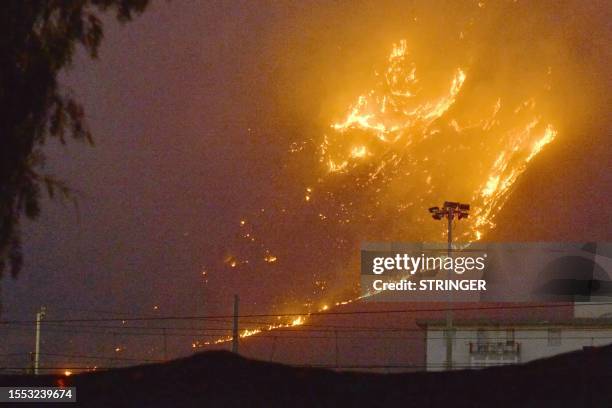 This photo obtained from Italian news agency Ansa shows a vast fire spreading on hills in the area of Monte Grifone and the town of Ciaculli around...