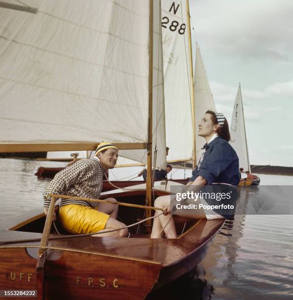 Man and a woman sailing a sailboat on Frensham Great Pond near Farnham in Surrey, England on 2nd August 1958. The man wears a black and white sweater...