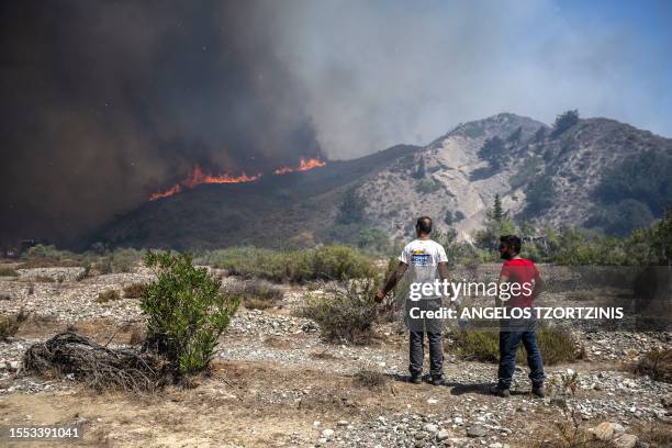 Locals watch the wildfires near the village of Vati, just north of the coastal town Gennadi, in the southern part of the Greek island of Rhodes on...