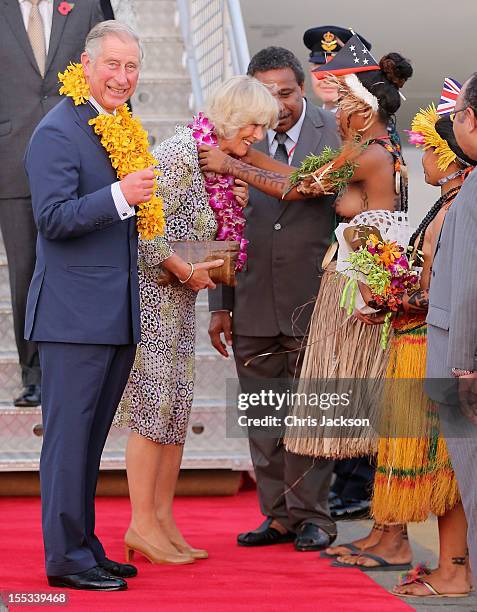 Topless dancer places garlands on Prince Charles, Prince of Wales and Camilla, Duchess of Cornwall as they arrive into Jackson's International...