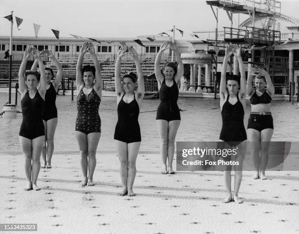 French women footballers in swimwear stretching during an exercise session in a swimming pool at Blackpool, Lancashire, England, 2nd July 1938.