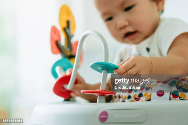 close up of adorable asian baby girl having fun playing in activity centre at home, with her little hands playing the montessori toy wire maze. explore and interact. learning through play. montessori education. baby's growth and development concept - bébé jeu photos et images de collection