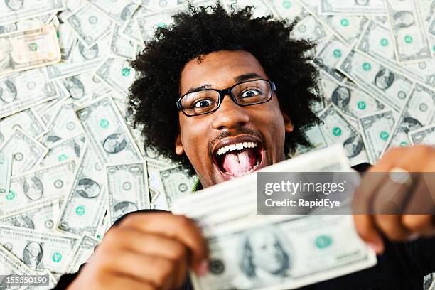 overjoyed young man surrounded by us dollars - money happiness stock pictures, royalty-free photos & images