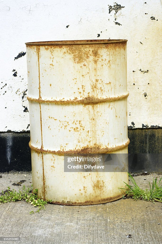 Rusty White Abandoned Oil Drum Against Factory Wall