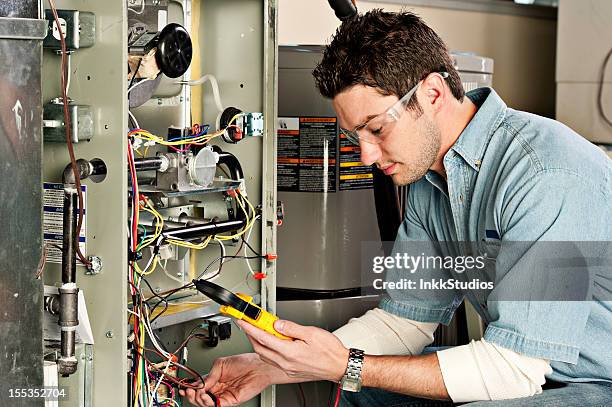 service technician testing a furnace. - air conditioner technician stock pictures, royalty-free photos & images