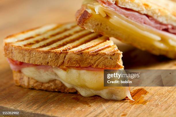 cheese and ham panini sandwiches on a wooden board - panini stock pictures, royalty-free photos & images