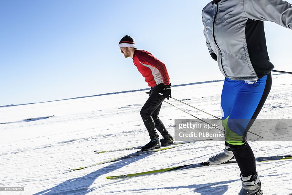 Male and female athletes cross-country skiing.