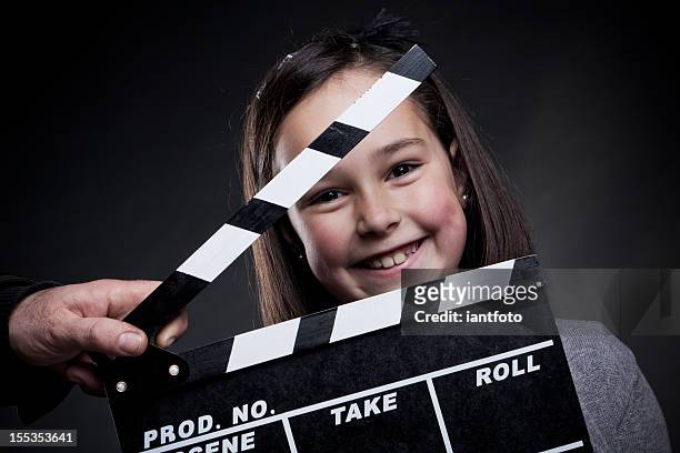 portrait of smiling young girl behind a movie clapper board - 2012 film stock pictures, royalty-free photos & images