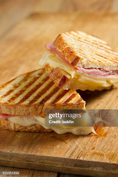 grilled ham and cheese panini sandwich on wood table - tosti stockfoto's en -beelden