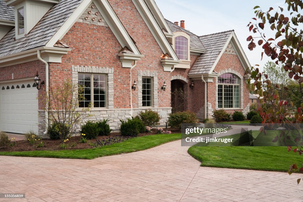 Lovely red brick upscale home with concrete driveway.