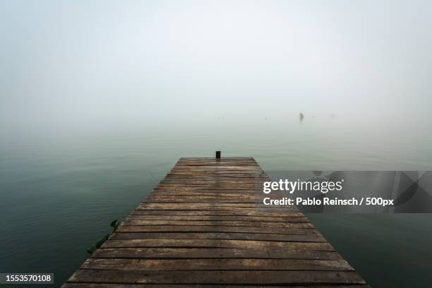 man on pier over lake against sky - ponton bois photos et images de collection