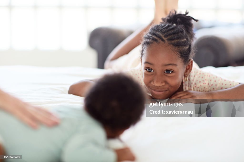 Affectionate young Black girl and baby brother face to face
