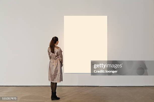 one woman looking at white frame in an art gallery - person standing infront of wall stockfoto's en -beelden