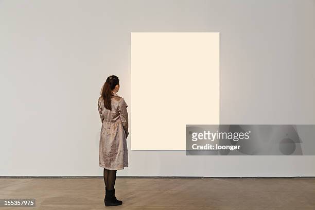 one woman looking at white frame in an art gallery - art fair stock pictures, royalty-free photos & images