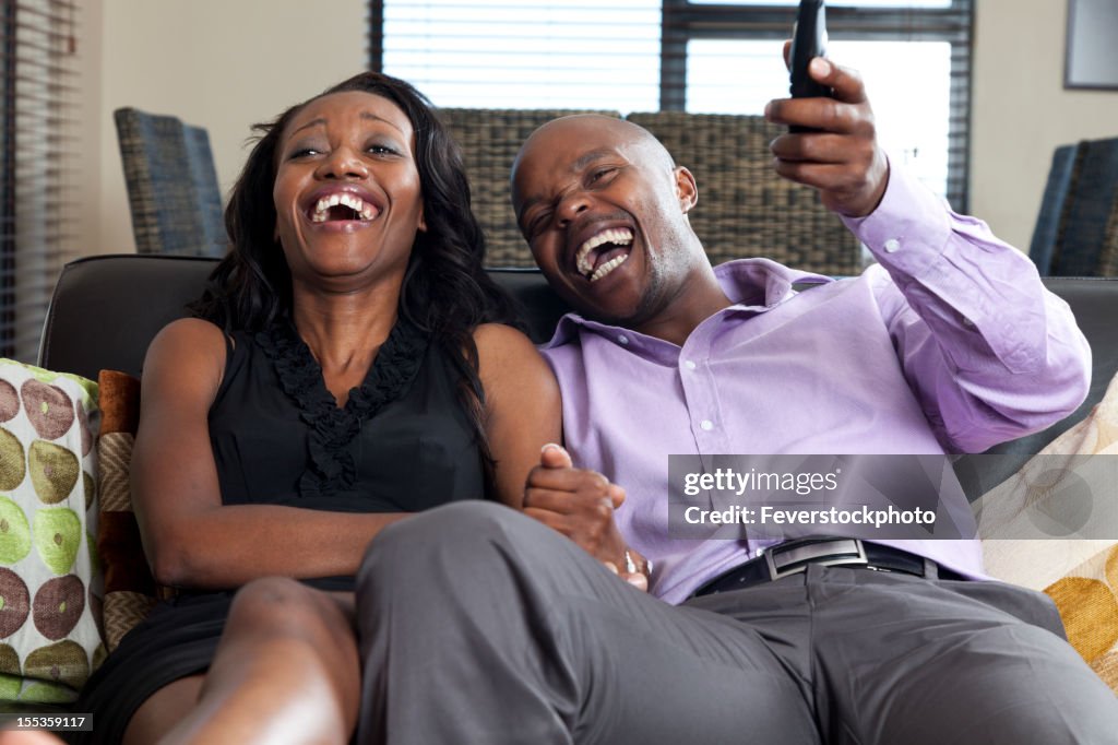 African Couple Relaxing Together At Home Watching TV And Laughing