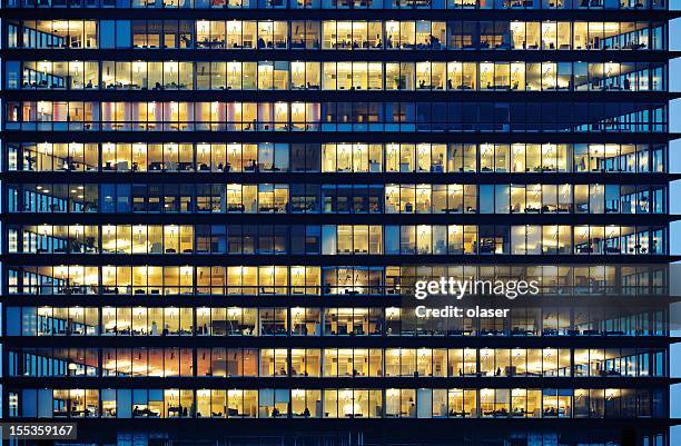 arbeitnehmer arbeitet spät. büro-fenster bei nacht. - office building stock-fotos und bilder