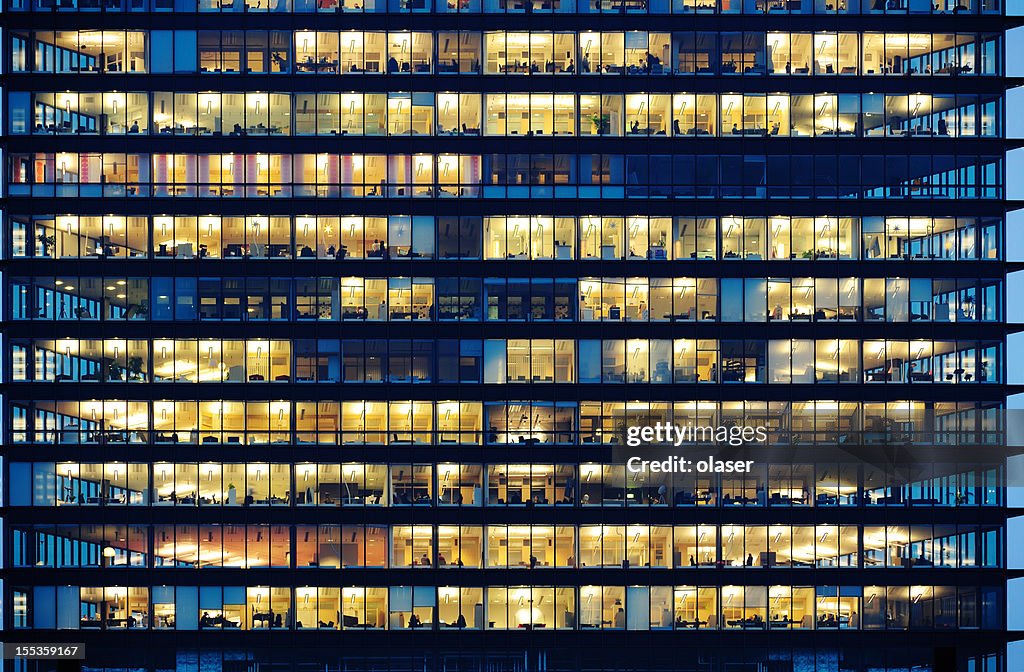 Workers working late. Office windows by night.