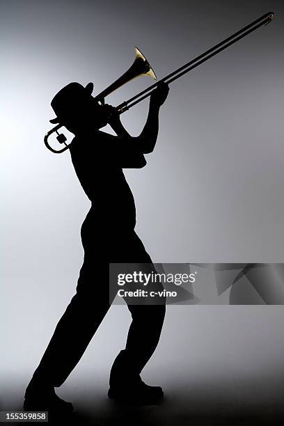 silhouette of a man in a porkpie hat playing the trombone - trombone stock pictures, royalty-free photos & images