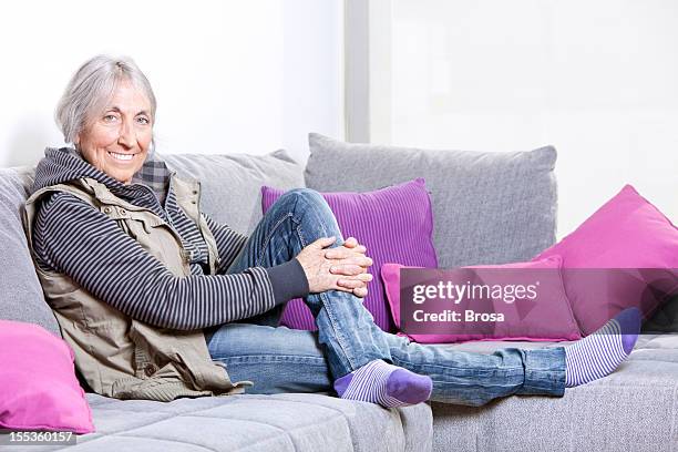 relaxed elderly woman on sofa - hand on knee stock pictures, royalty-free photos & images