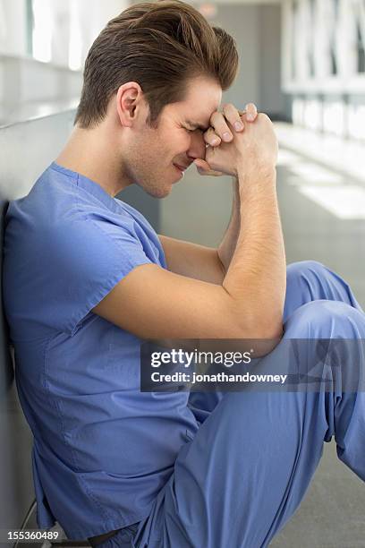 young man in blue scrubs - nurse praying stock pictures, royalty-free photos & images