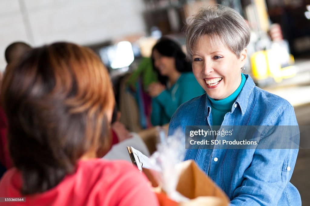 Mature woman greating people at a donation center