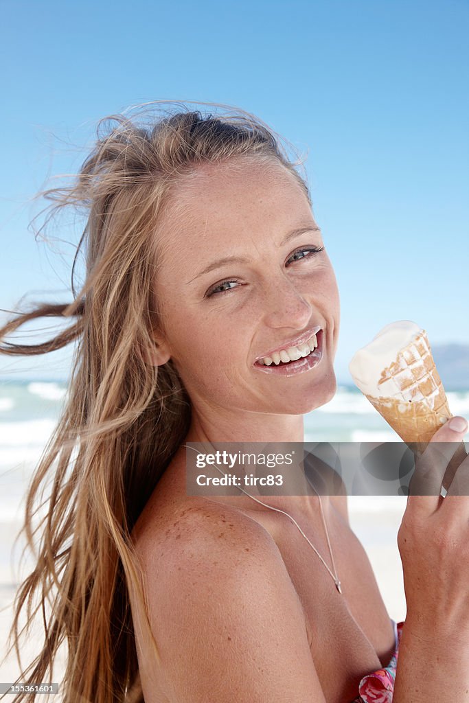 Attractive blonde woman eating  ice cream at the beach