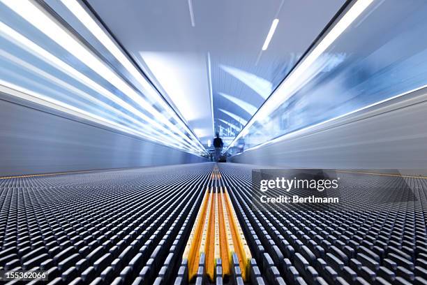 person on a moving escalator with yellow stripes - abstract direction stock pictures, royalty-free photos & images